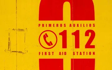 Yellow and red first aid sign with the emergency number 112