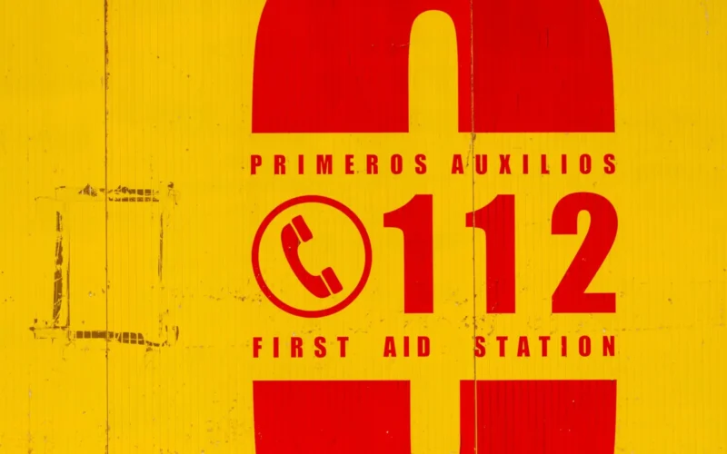 Yellow and red first aid sign with the emergency number 112