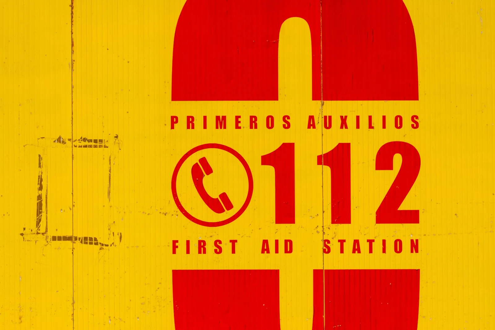 Yellow and red first aid sign with the emergency number 112