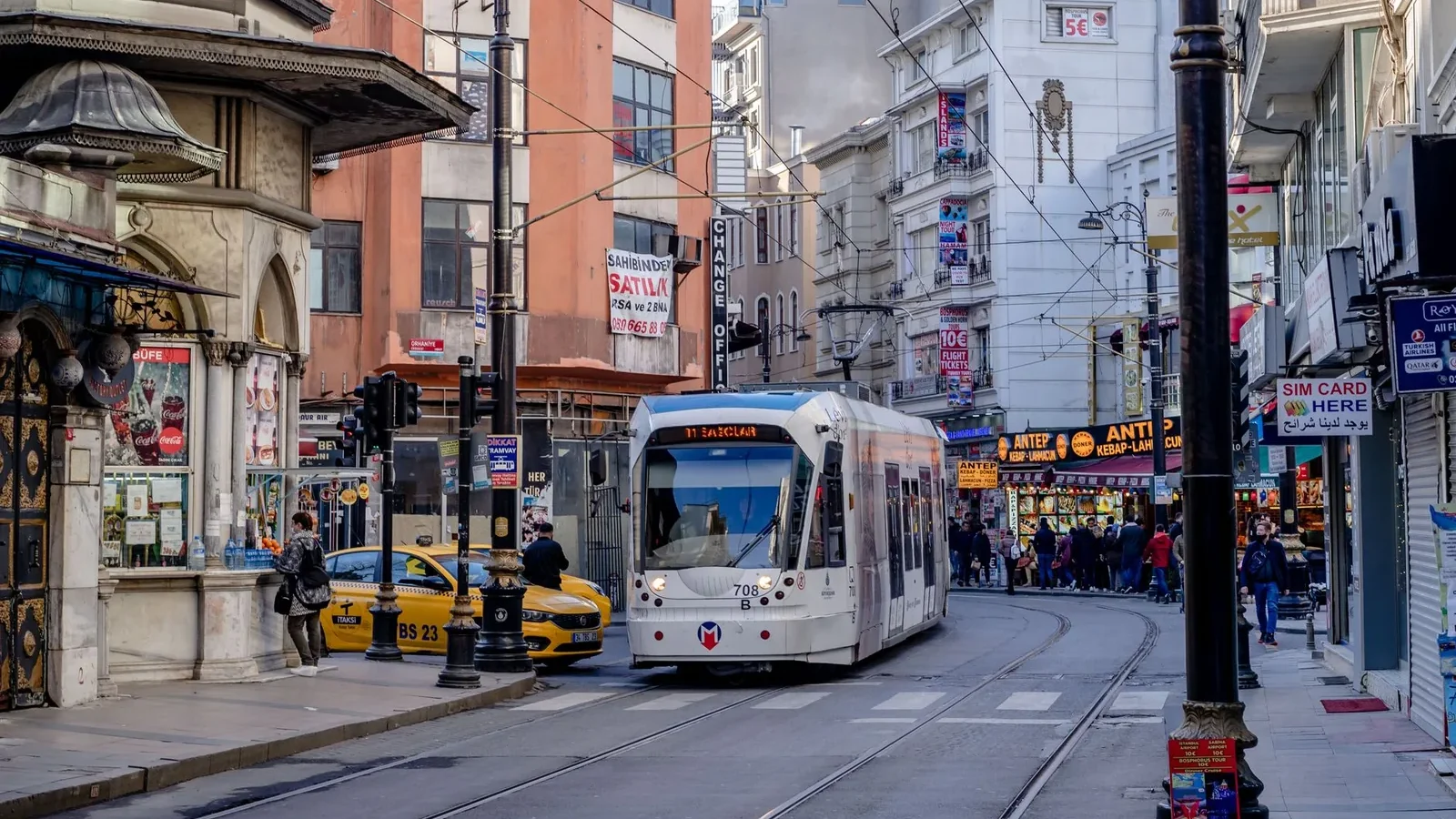A modern tram passing through a busy Istanbul street