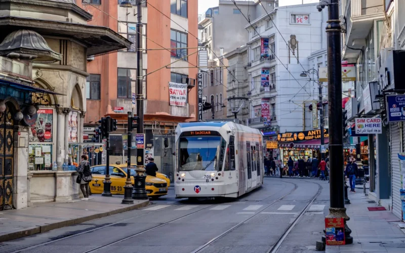 A modern tram passing through a busy Istanbul street