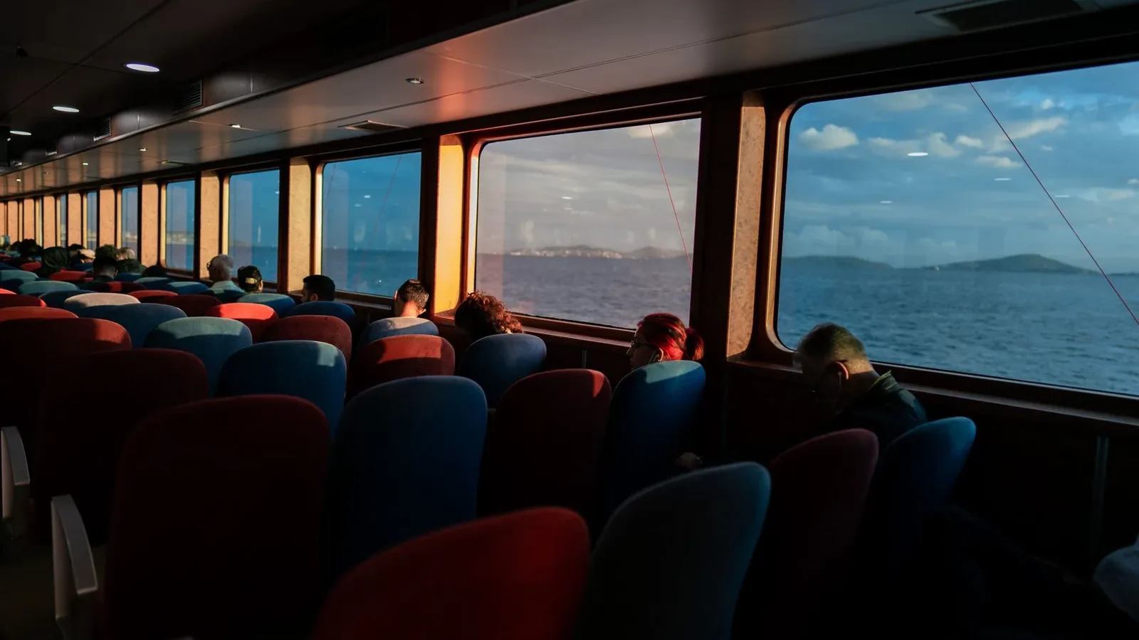 Passengers sitting by the windows of an Istanbul ferry at sunset