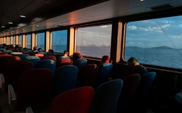 Passengers sitting by the windows of an Istanbul ferry at sunset