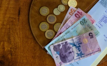 Turkish lira coins and banknotes on a wooden table next to a receipt